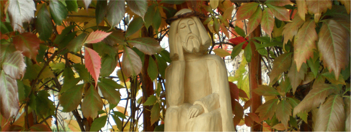 Na postumencie znajduje się drewniana figurka przedstawiająca postać siedzącego Jezusa. Otaczają ją liście.
