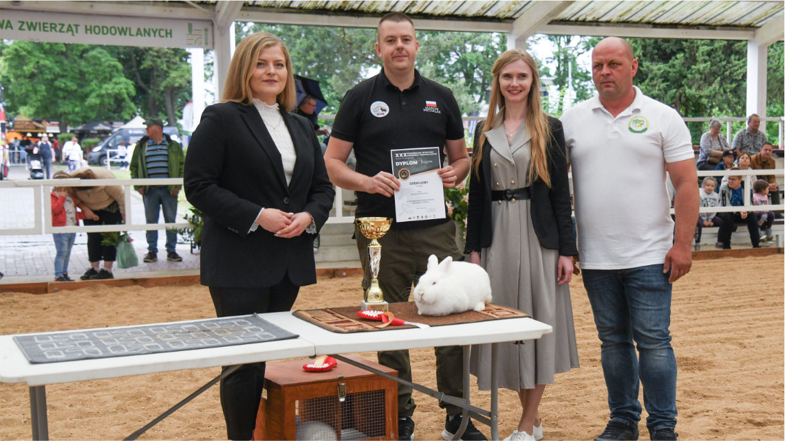 Marcin Michalak (z dyplomem), hodowca czempiona w rasie królik nowozelandzki biały. Puchar i dyplom wręczali (od lewej): Justyna Winiarska, dyrektor WODR w Poznaniu; Wioleta Barczak, komisarz XXX RWZH w Sielinku oraz Artur Handzel, prezes KZHK